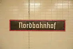 Bahnhofsschild in Schriftart Tannenberg an einer Hintergleiswand, 2023