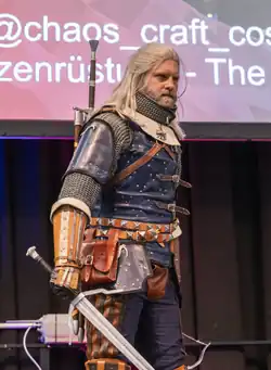 Cosplayer schaut von sich aus konzentriert nach links. Rüstung mit blauem Leder davor, Katzenaugen