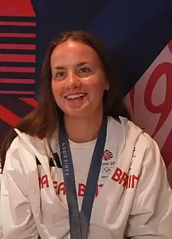 Lauren Henry trägt weiße Trainingskleidung, um den Hals ein Band mit Medaille.