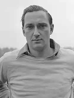 Schwarzweißfoto von Mulder, der über einem Hemd einen Pullover trägt.