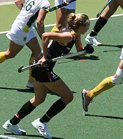 Lisa Nolte im schwarzen Nationaldress läuft, den Schläger mit beiden Händen festhaltend.