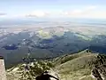 Blick vom Gipfel nach Südosten (unten: Skalnaté pleso (1751&nbsp;m) + Tatranská Lomnica (850&nbsp;m), hinten rechts: Poprad (672&nbsp;m))