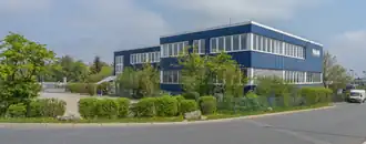 Das Foto zeigt eine Niederlassung von M&M in Hof-Hohensaas. Das Gebäude ist blau.