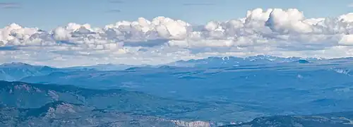 Ein sanft geneigtes Gelände ragt über bewachsene Hänge mit Bergen im Vorder- und im Hintergrund.