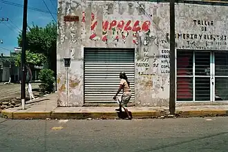 Einsame Spaziergängerin vor einer heruntergekommenen Hausfassade