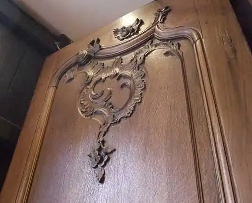 Schranktür Rokoko, anno 1750&nbsp;– Authentische Konstruktion aus Rahmen und Füllung&nbsp;– Schnitzereien und Profile aus dem vollen Holz geschnitten. Hinweis: Ein aufrechter Riss in der Füllungs­schnitzerei rechts oben und offene Fugen beim Stoß der Rahmen­teile wurden verursacht durch das „Arbeiten“ des Holzes wegen seiner hygroskopischen Eigenschaften.