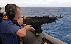 Der britische Commodore Fitzsimmons feuert bei einem Besuch auf der USS Nashville ein M240 Maschinengewehr ab, Januar 2009