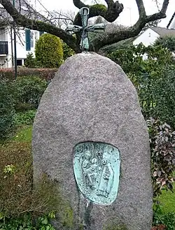 Ein frei stehender Steinblock mit einem eingelassenen Relief, das im Nächsten Bild in Nahaufnahme gezeigt wird.