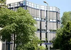 Ansicht eines glasverkleideten Hauses mit Bäumen davor.