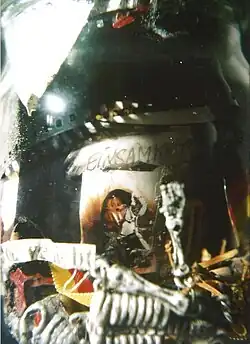 Nahaufnahme eines Einmachglases, das nicht näher definierte Gegenstände zeigt. Es ist das Wort EINSAM zu sehen.