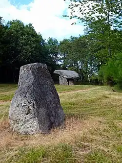 Menhir von Chez Moutaud im Hintergrund der Dolmen
