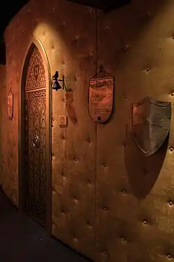 Innenraum des Minnehus in Lajen mit der symbolischen Darstellung von Walthers Lehen. Die gotische Tür repräsentiert den Eingang zu seinem ersehnten Besitz, davor die Klingel mit dem Vogel als Verweis auf den „Vogelweider“