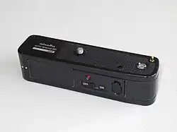Die so genannten Winder waren eine weniger leistungsfähige und preisgünstige Alternative zum Motor für Kleinbild-SLRs, hier Minolta Auto Winder D aus den 1970ern