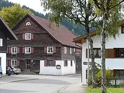 zweigeschossiger, verputzter bzw. verschindelter Blockbau mit Satteldach