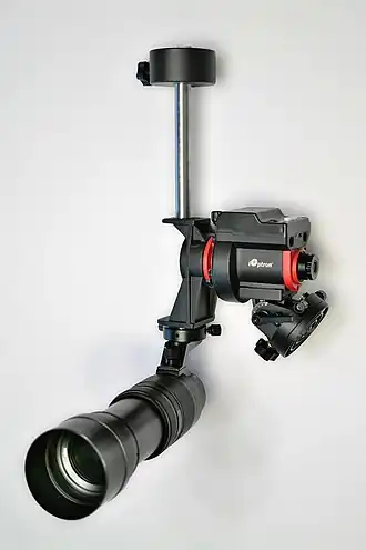 Deutsche Montierung für die astrofotografische Langzeitbelichtung mit optischem Polsucher (rechts in der Mitte), Teleobjektiv (unten) und Gegengewicht (oben). Die justierbare Basis unter dem Okular des Polsuchers mit Dosenlibelle dient zur Befestigung und Ausrichtung auf einem Stativ. Das elektronisch gesteuerte Gerät ist akkubetrieben und dreht die Polachse des äquatorialen Koordinatensystems auf der optischen Achse des Polsuchers über ein Getriebe mit einem Elektromotor synchron zum beobachteten astronomischen Objekt.