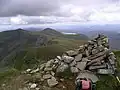 Der Gipfelcairn des Aonach air Chrith, im Hintergrund der Druim Shionnach (links), der Creag a’ Mhaim (Mitte), dahinter Loch Loyne
