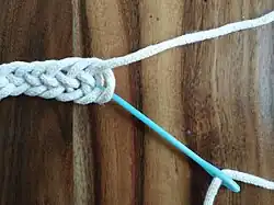 Schritt 1: UO = 1× unter einem Schlingenbogen hindurch, 1× über einen Schlingenbogen hinweg (anschließend Nadel durchziehen)