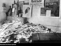 Raum mit Tafeln, Postern und Zetteln an der Wand, am Boden kniehoch Bücher und Zeitschriften