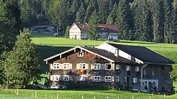 zweigeschossiger, verschindelter Blockbau mit Flachsatteldach