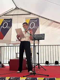 Bild von Odile Kennel, sie steht auf einer Bühne und performt Gedichte.