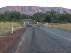 Dies Farbfoto zeigt eine befahrbare und Teil einer australischen Landstraße bildende Brücke über den Fluss Dunham River im unbesiedelten Gebiet in der Region Kimberley im Nordosten des australischen Bundesstaates Western Australia, im Hintergrund am Horizont sind die dortigen Berge zu sehen. Es wurde 2004 aufgenommen.