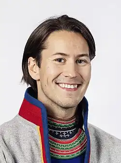 ein braunhaariger Mann, der in die Kamera lächelt und eine samische Tracht trägt