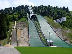 Die Olympiaschanze in Garmisch-Partenkirchen im Mai ohne jeden Schnee wirkt wie eine in einen Hang hineingebaute futuristische Großskulptur in grünbläulicher Farbe