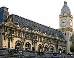 Fassade über der Eingangshalle mit Uhrturm, hinter den Bogenfenstern das Restaurant Le Train Bleu