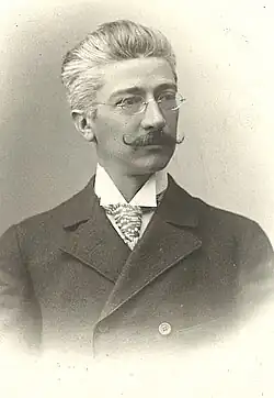 Paul Czermak mit Brille, Schnurrbart, gepunkteter Krawatte und dunklem Anzug