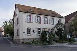 Ein weißes, zweigeschossiges Gebäude mit rotem Satteldach