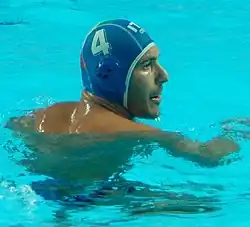 Pietro Figlioli ist während eines Spiels im Wasser, er trägt eine blaue Bademütze mit der weißen Nummer 4.