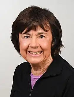 Ein Porträt von Ingrid Grummt: Sie hat kurze dunkle Haare mit Pony, ist schon etwas älter und trägt eine dunkle feine Wolljacke mit Reißverschluss über einem dunkelrosa T-Shirt, von dem nur der Ausschnitt rausschaut.