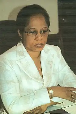 Cécile Manorohanta. Eine afrikanische Frau mit kurzer Kraushaarfrissur in einem weißen Blazer. Sie sitzt da mit verschränkten Armen.