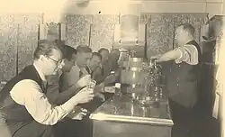 Werner Saam (rechts) zapft 1940 Bier hinter der Theke anlässlich des Geburtstags von Anton Metzen (2.v.l.).