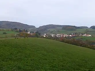 Blick von einem Wirtschaftsweg südwestlich von Kolmbach ostnordostwärts zum Raupenstein: Neunkircher Höhe (links), Raupenstein (mittig bis rechts) und Kolmbach (mittig)