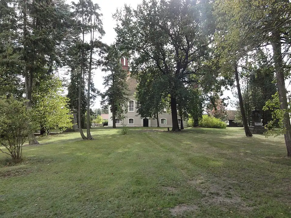 Kirchhof der Kirche in Reichwalde, mittig die Luthereiche, seitlich die Denkmale