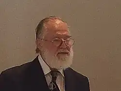 Porträtfoto von Reinhard Bölling von 2016, nach rechts blickend mit Brille, zurückgekämmten Haaren und weißen Vollbart