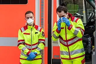 Mitarbeiter des Rettungsdienstes der Berufsfeuerwehr der Stadt Köln beim Anlegen von FFP-Masken zum Infektionsschutz