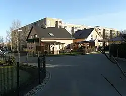 Im Vordergrund eine kleine Siedlung mit Einfamilienhäusern, im Hintergrund DDR-typische Plattenbauten, alles Roßweiner Ring