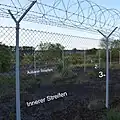 Die Dreifachumzäunung mit einem äußeren und einem inneren Streifen