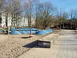 Sandkiste mit maritimen Motiven wie Wellen und Treibholz