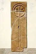 Romanische Grabplatte mit dem Motiv eines Kreuzstabes an der äußeren Kirchen-Südwand