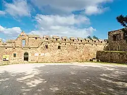 Steinerner Wehrgang mit Steintreppe, Zinnen und Kragsteinen auf der westlichen Ringmauer der Vorburg; mit Portal zum Altan