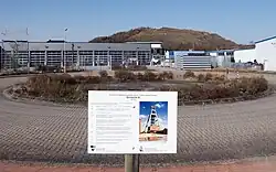 Betonierter Schachtdeckel von Schacht III im Gewerbegebiet vor der renaturierten Abraumhalde des Kaliwerks Hansa