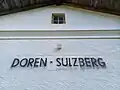 Bahnhofsschild, unter der letzten Aufschrift scheint der ursprüngliche Name Doren durch