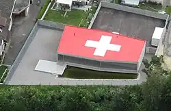 Haus mit Schweizerkreuz auf dem Flachdach[10][11]