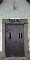Zweiflügelige Holztür (ersetzt&nbsp;1997) IHS-Monogramm und Jahreszahl der Erbauung im Türsturz, Herz-Jesu-Figur in der Mauernische (ersetzt&nbsp;2017)