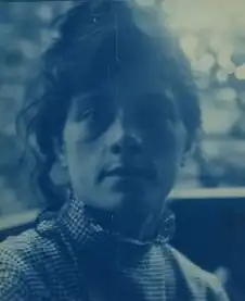 Helle und dunkle Blautöne zeigen eine Porträtaufnahme von Susan Macdowell Eakins. Sie hat langes dunkles Haar, das locker zusammengebunden ist.