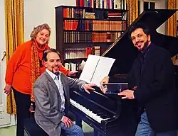 Siegrid Ernst steht mit Maximiliano de Brito und Renato Mismetti an einem Flügel, 2014
