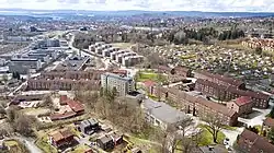 Drohnenaufnahme einer Stadt mit Hochhäusern im Vordergrund und etwas weiter entfernt kleinere Häuser